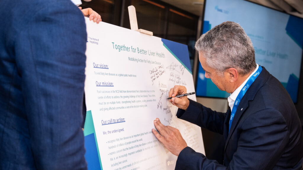 Dr. Mário Pessoa firmando un afiche, reafirmando el compromiso de ALEH en la salud hepática.